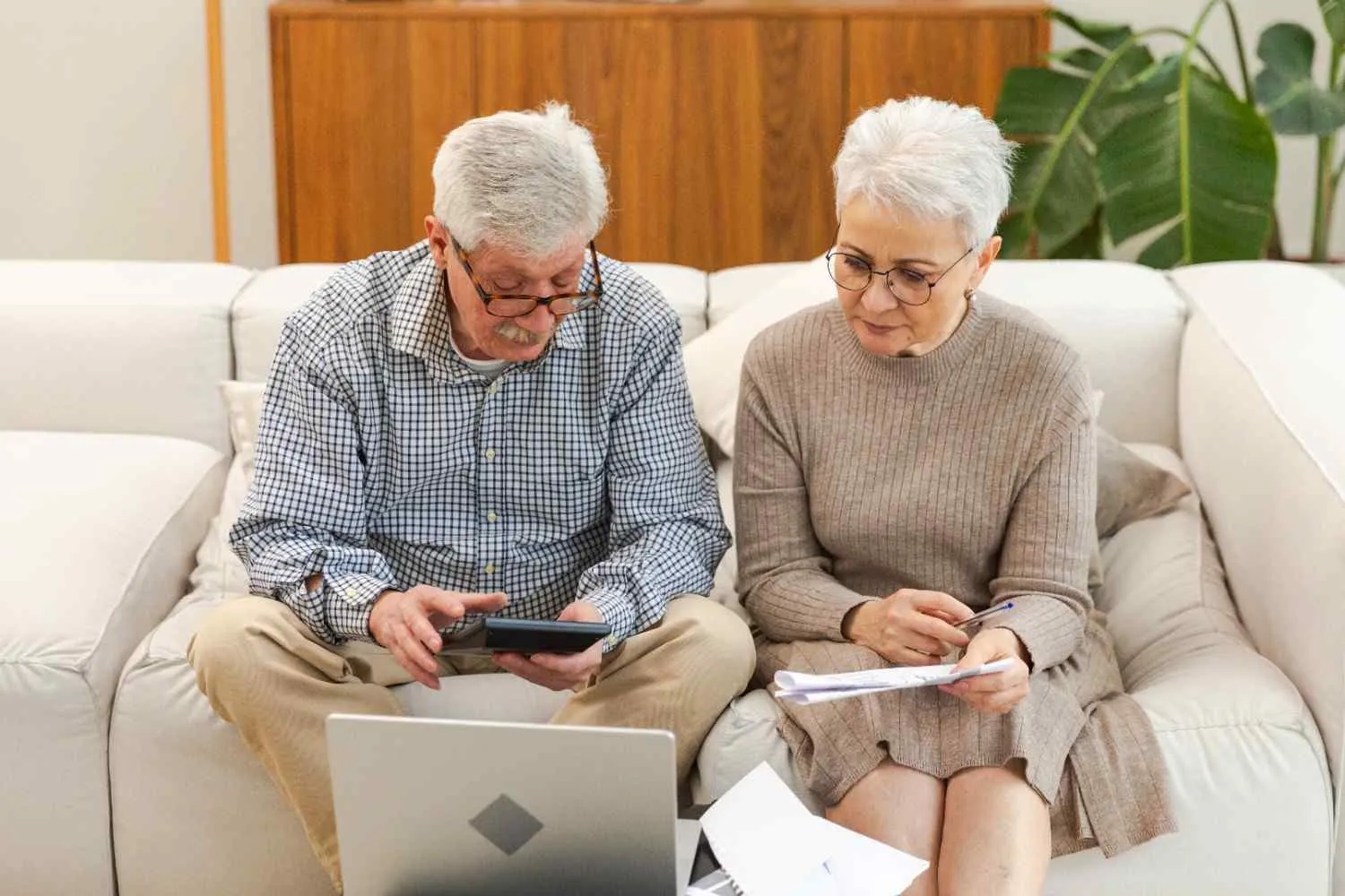 Older couple going through Medicare paperwork and costs at home